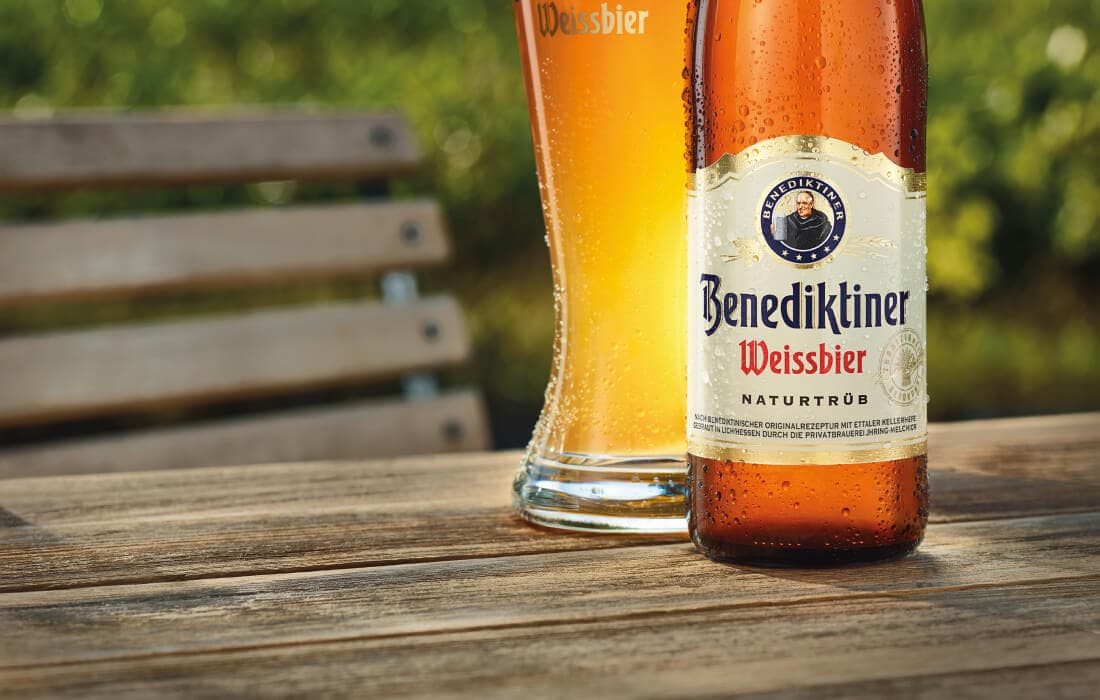 Ly Weissbier đặt cạnh chai Benediktiner Naturtrüb 500ml trên bàn gỗ